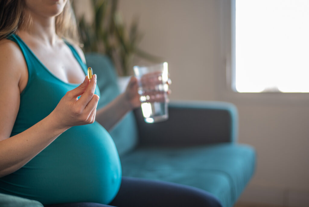 mulher grávida segurando comprimindo e um copo de água