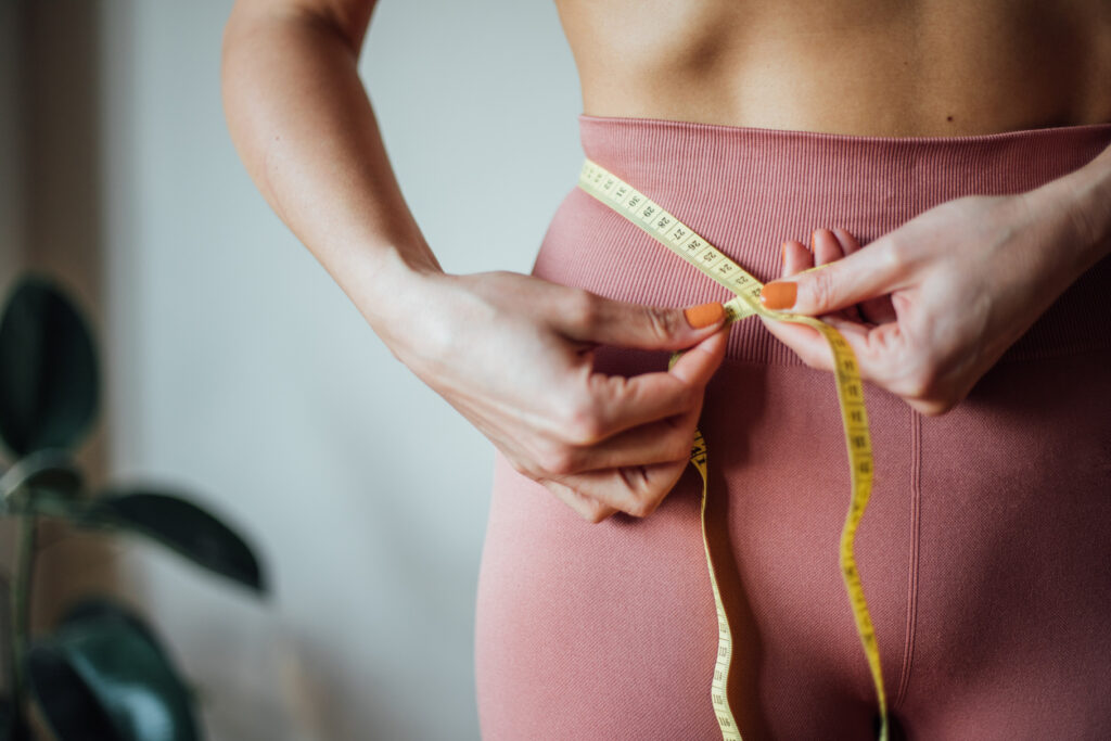 Corpo feminino, sendo medido por uma fita métrica