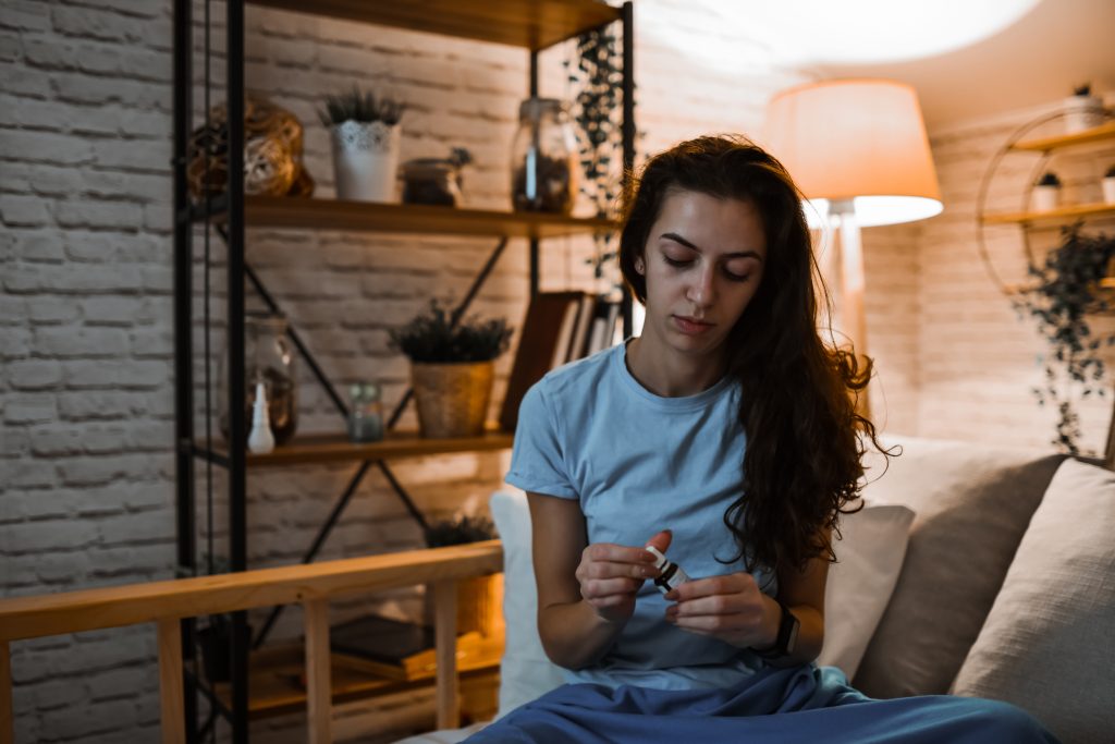 Menina sentada no sofá tomando melatonina.